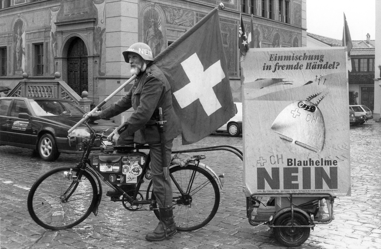 Hombre en bicicleta con un bandera de Suiza y un cartel de votaciones en 1994