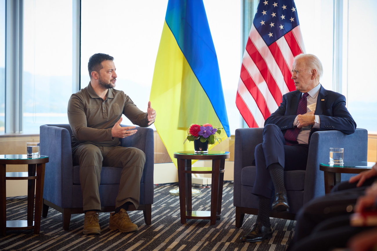 zelensky e biden conversano seduti su due poltrone e dietro di loro le bandiere dei loro rispettivi paesi