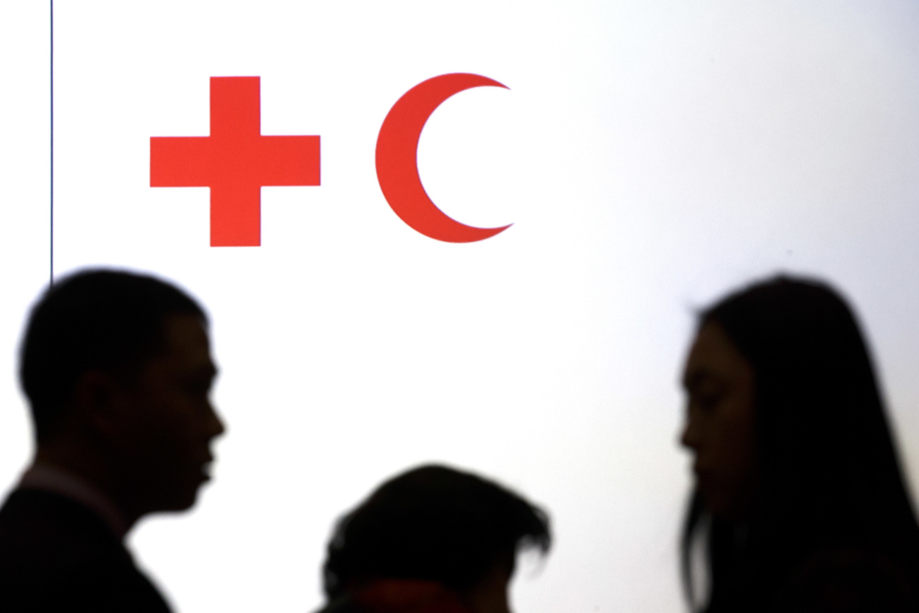 Picture of shadows of people over the symbols of the International Federation of Red Cross and Red Crescent Societies