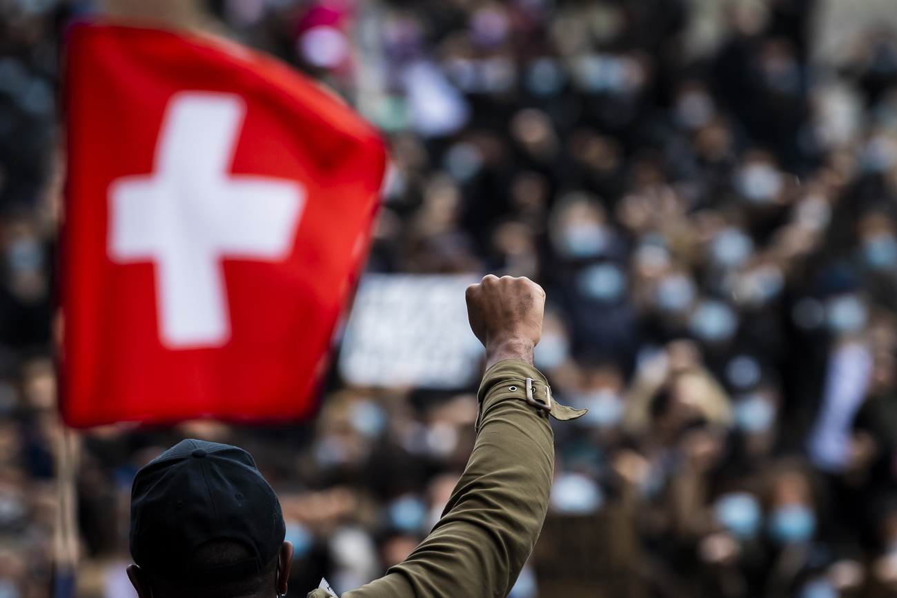 Eine erhobene Faust vor einer Schweizer Flagge.