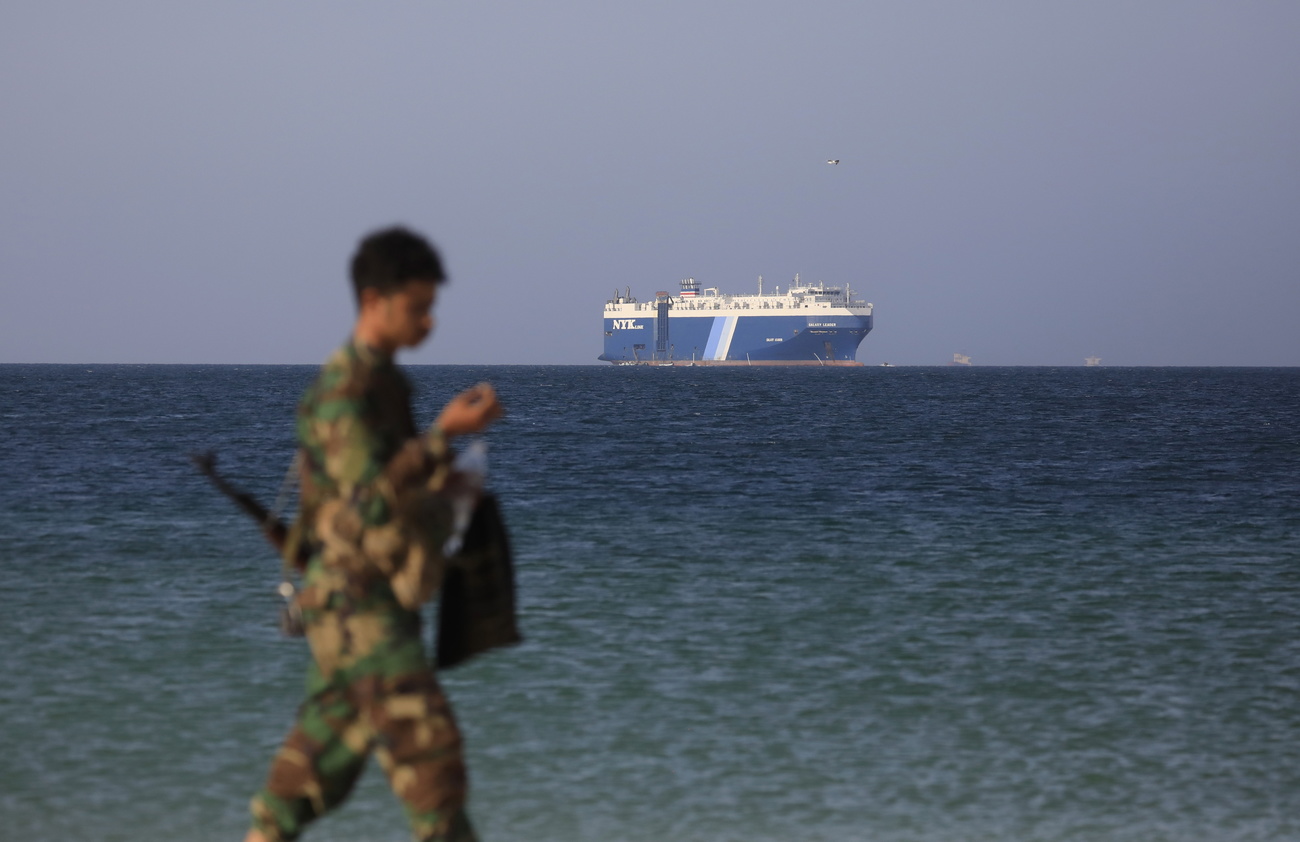 soldato cammina su spiaggia, sullo sfondo, nel mare, una nave cargo