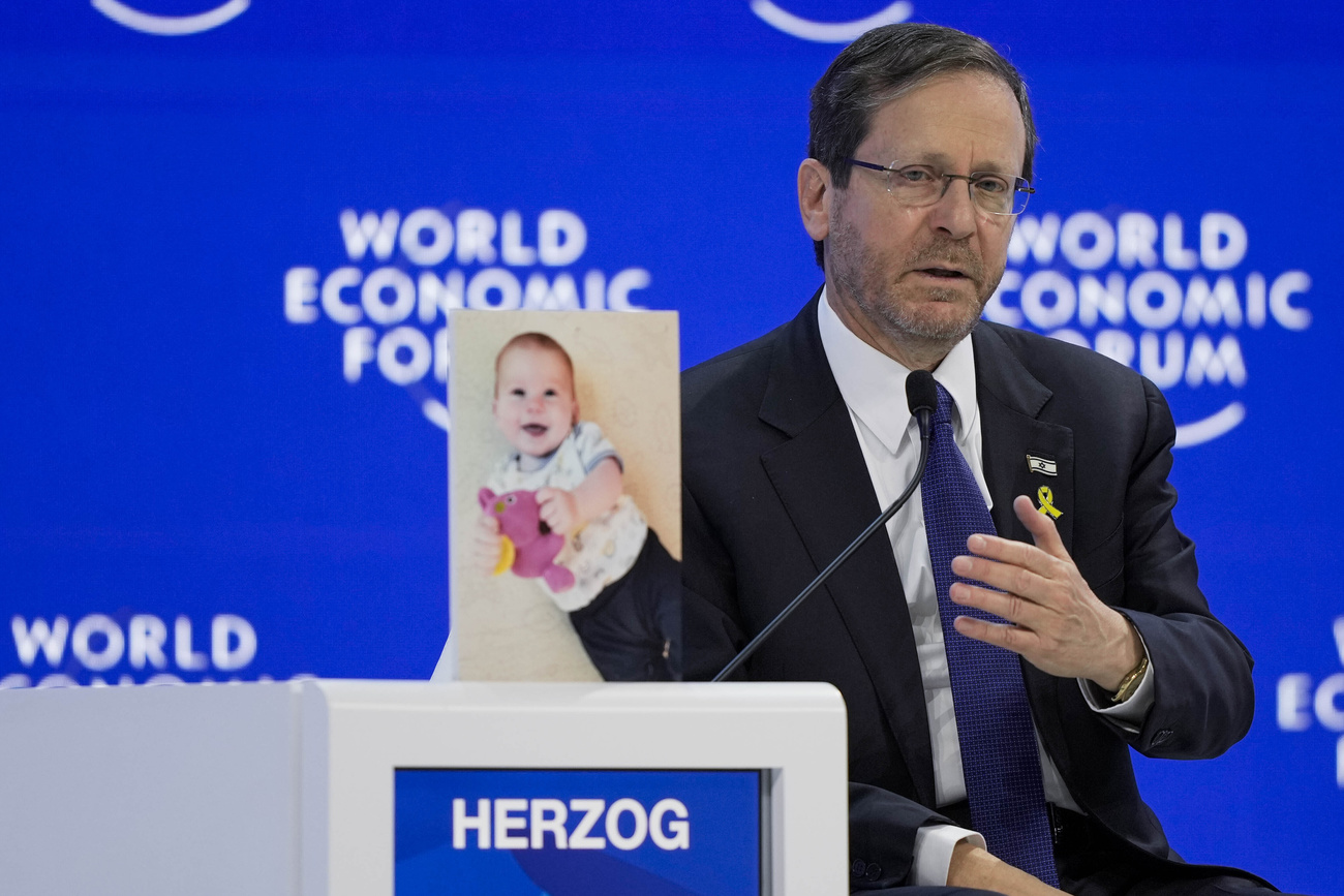 isaac herzog parla al wef, accanto a lui la foto di un bebè