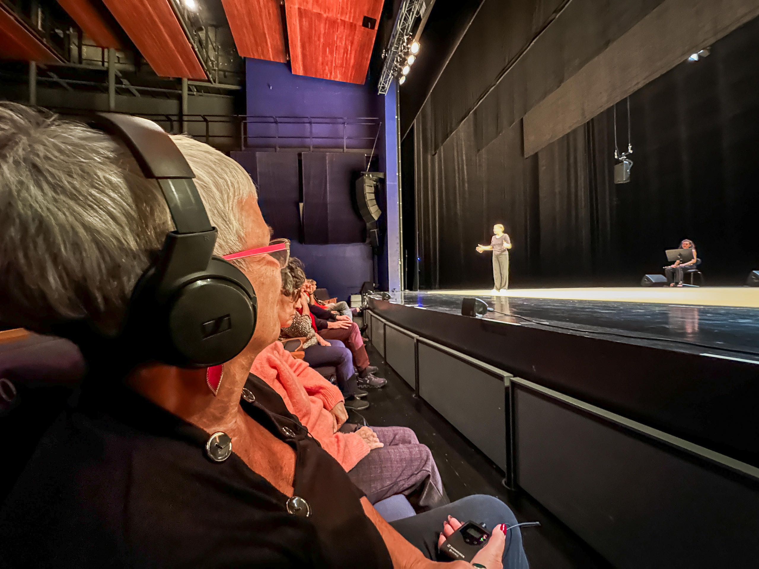 Femme portant un casque audio, assise au premier rang d une salle de théâtre
