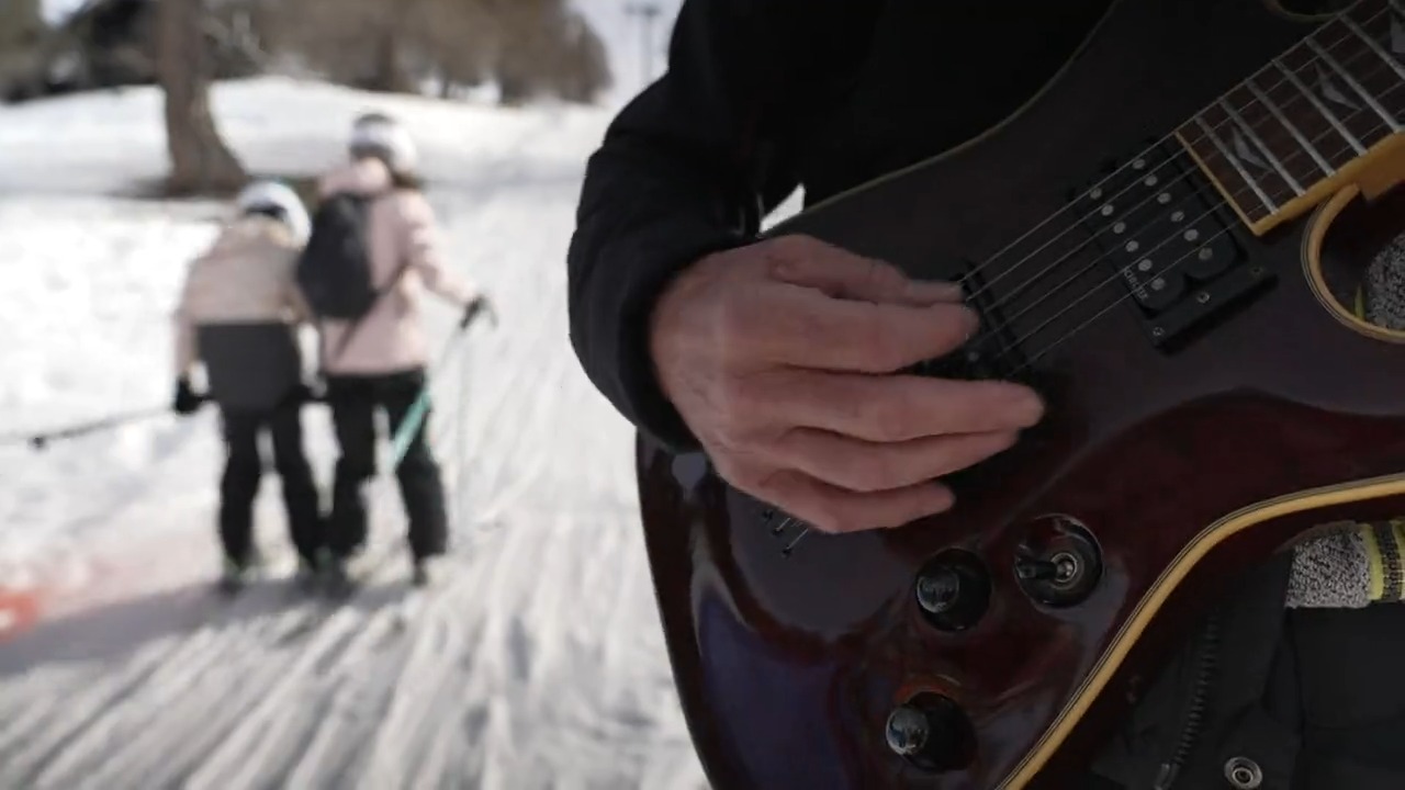 uomo con chitarra e sciatori