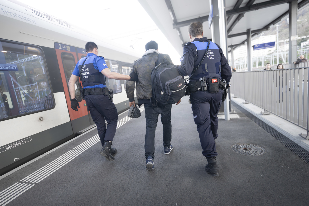 Due guardie di frontiera scortano un immigrato alla stazione di Chiasso.