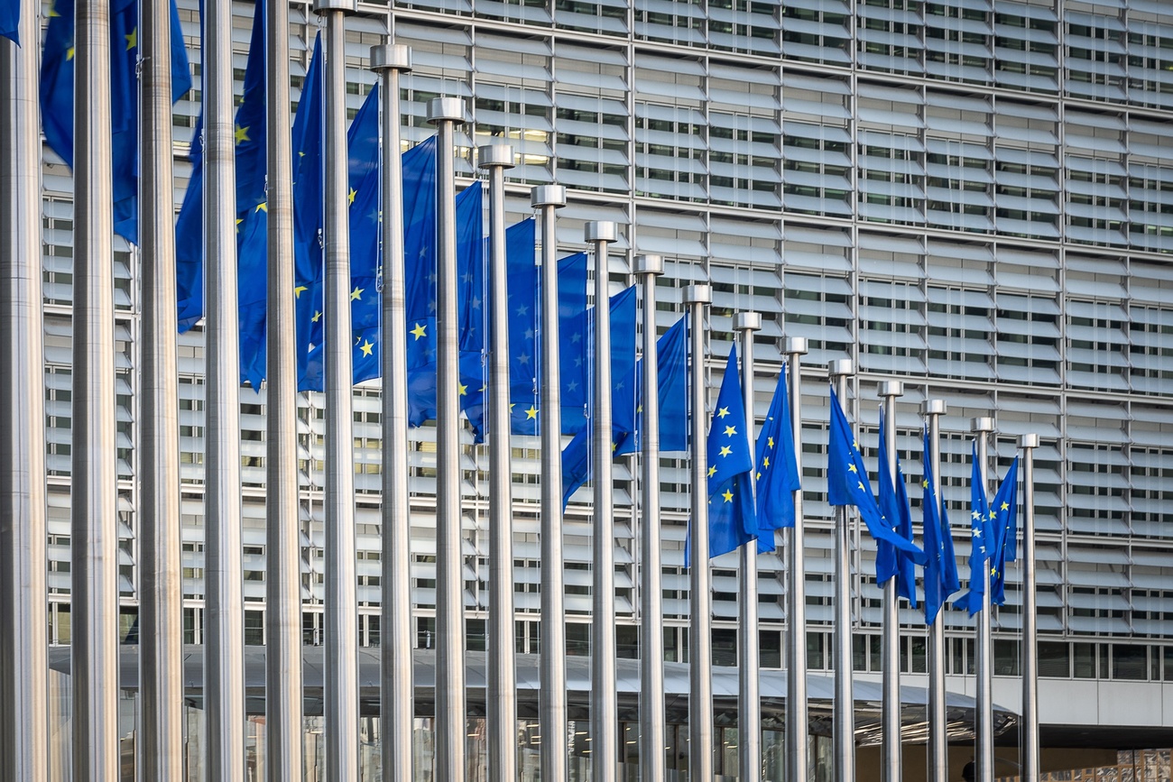 Una fila di bandiere blu con le stelle dell'UE davanti al palazzo della Commissione UE a Bruxelles.