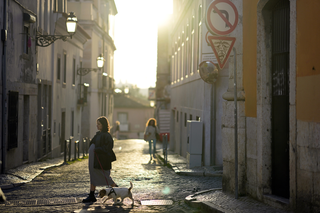 People walk in the street in the Bairro Alto, or High Quarter, neighborhood in Lisbon as the sun sets