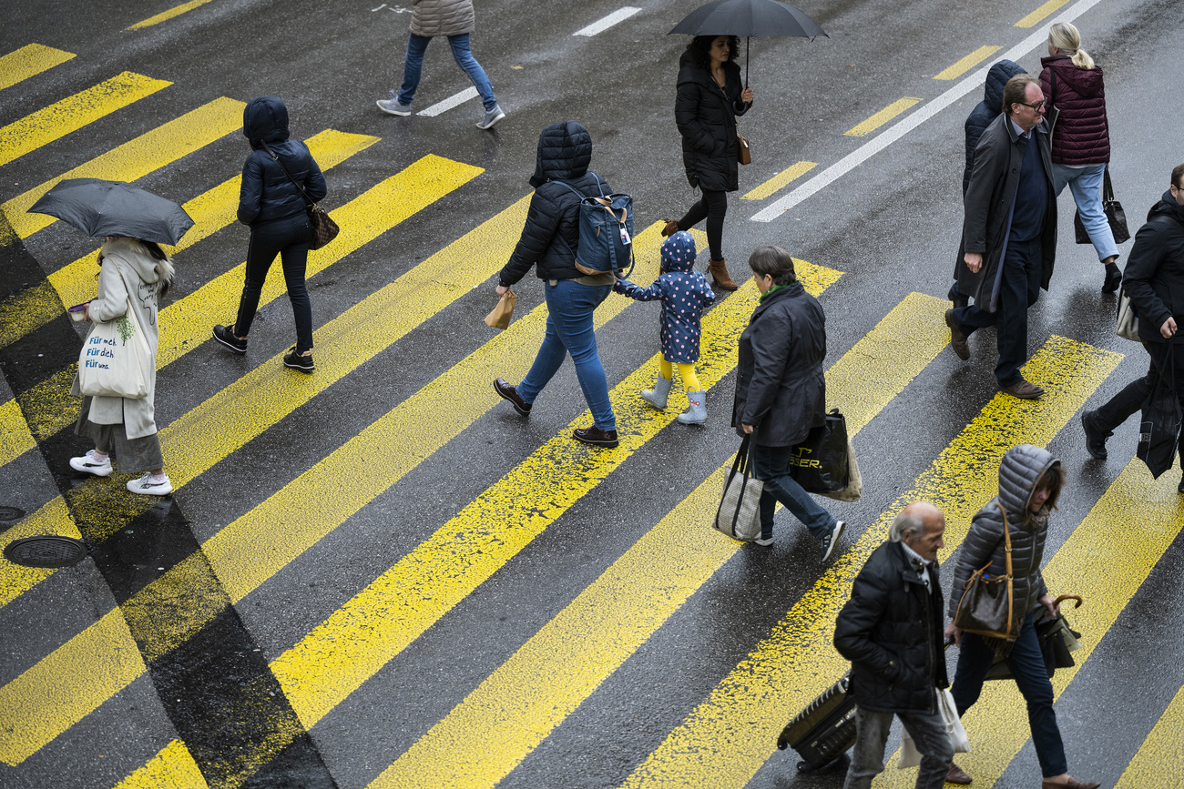 Diverse persone attraversano le strisce pedonali.