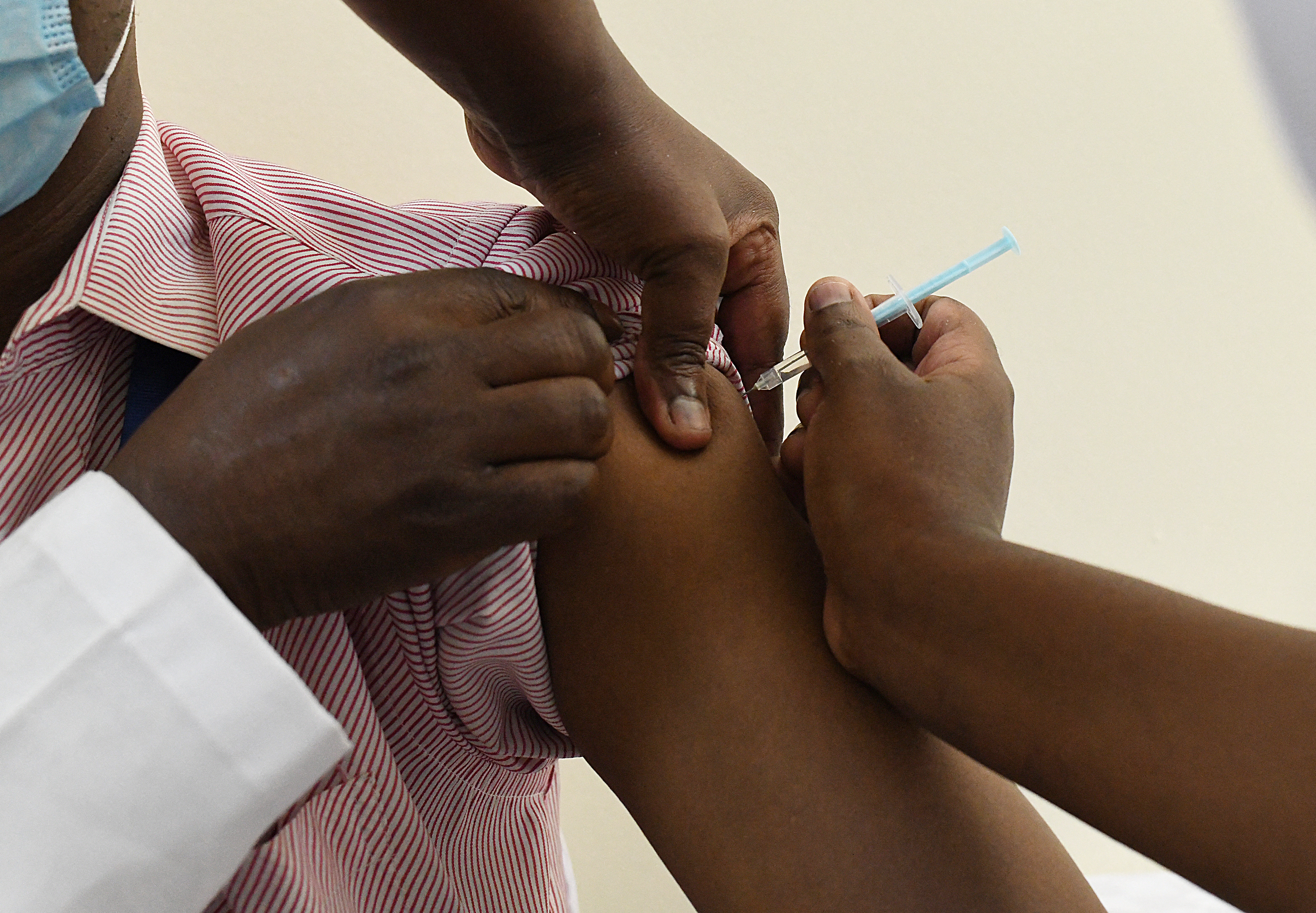 Shoulder of an African person being injected wih a vaccine