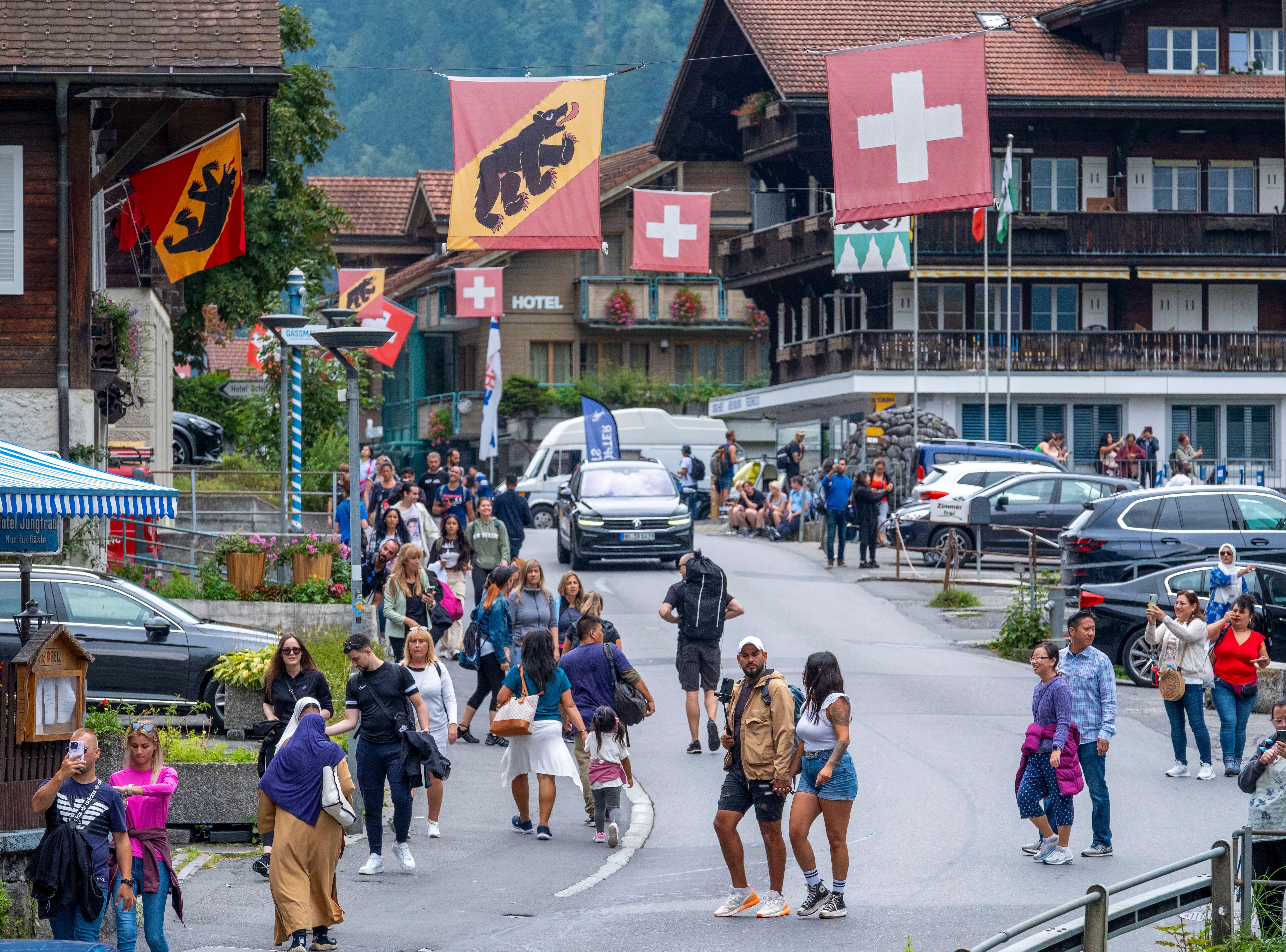 ラウターブルンネンを歩く観光客とスイスの国旗