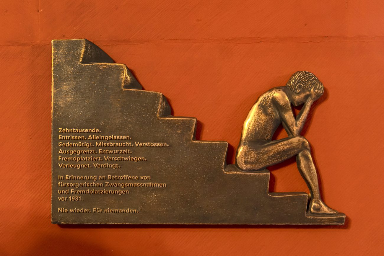 targa comemmorativa in bronzo che ritrae persona che piange seduta su scale