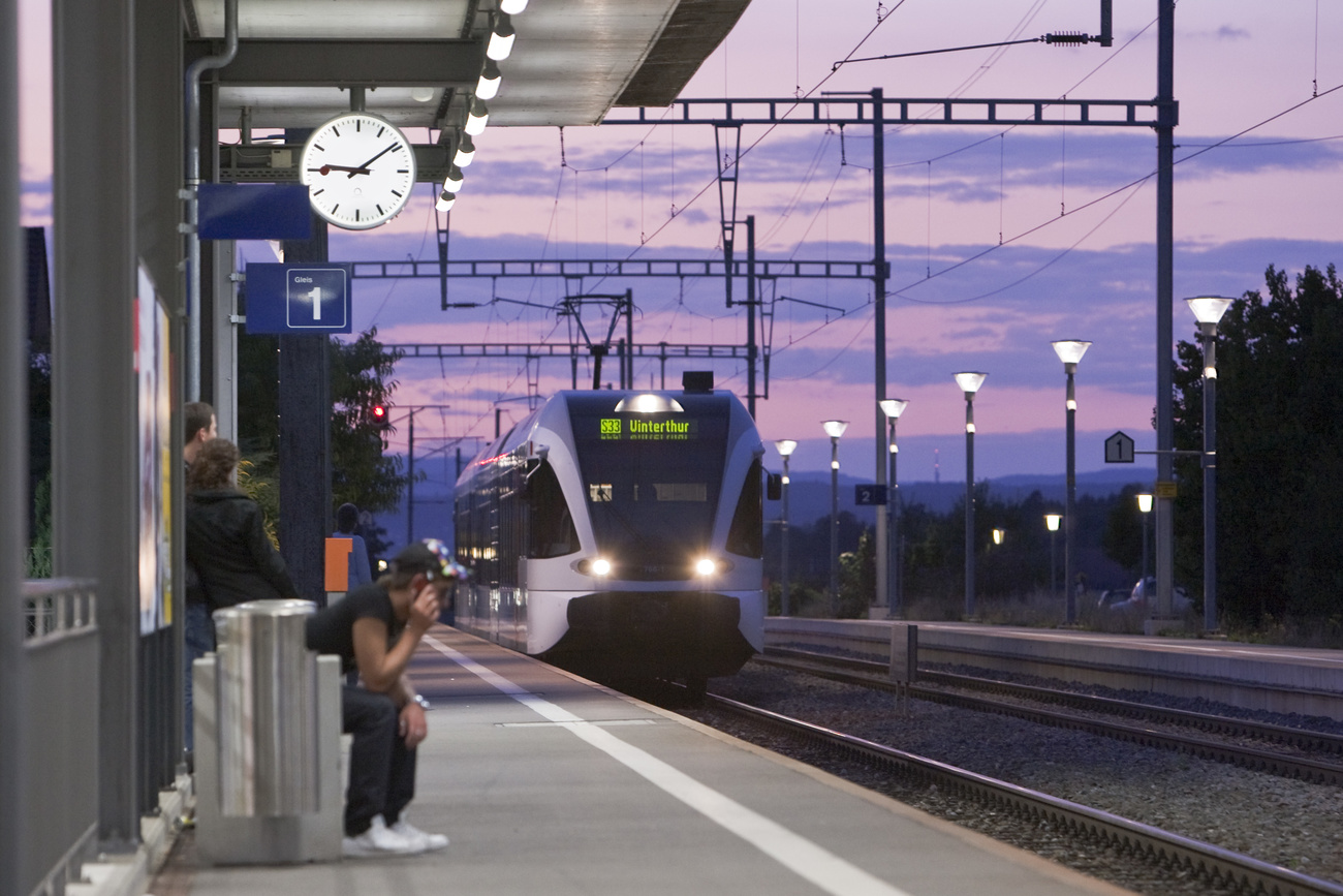 Un treno entra in una stazione di periferia.