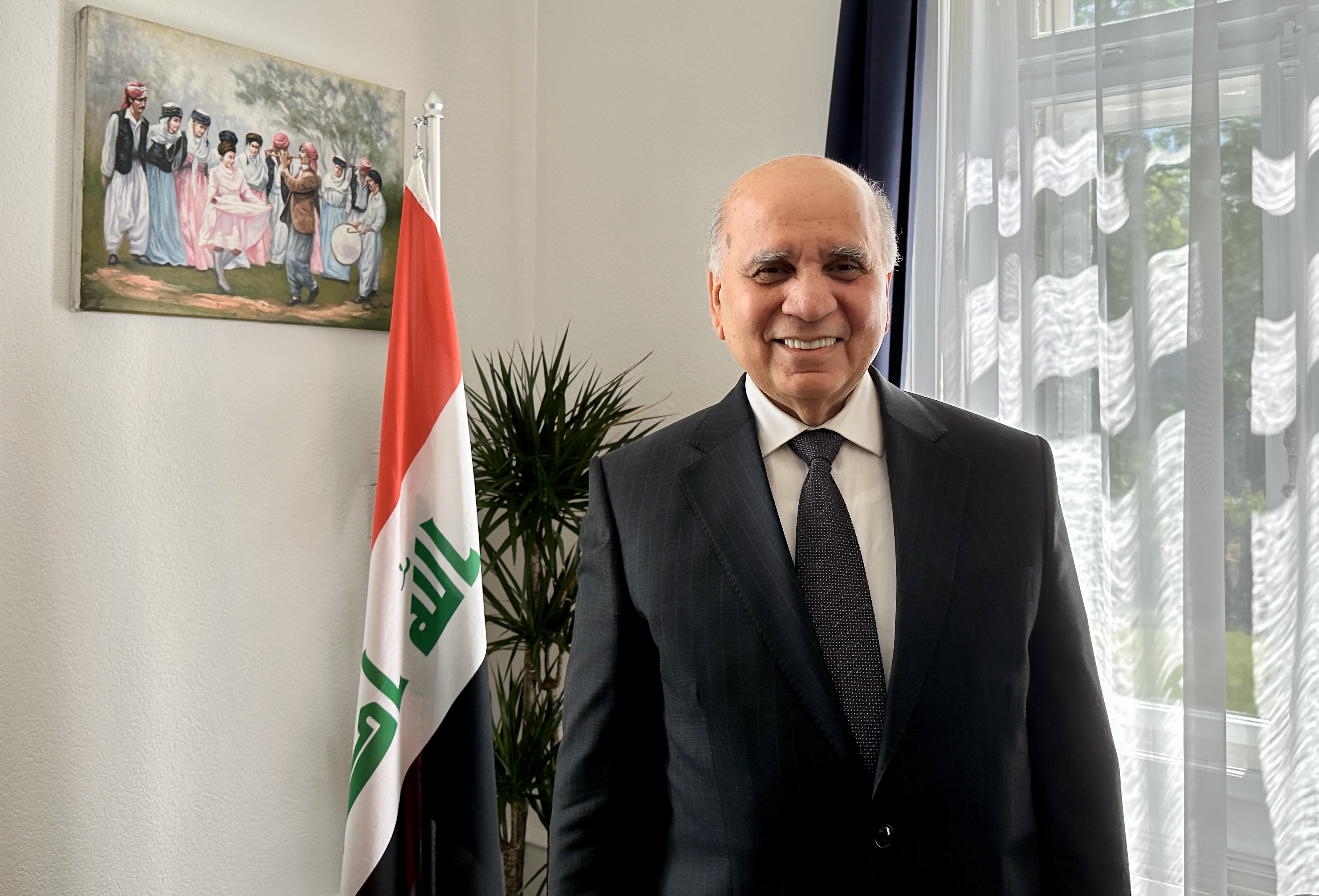 Fuad Hussein vor einer Flagge des Irak.