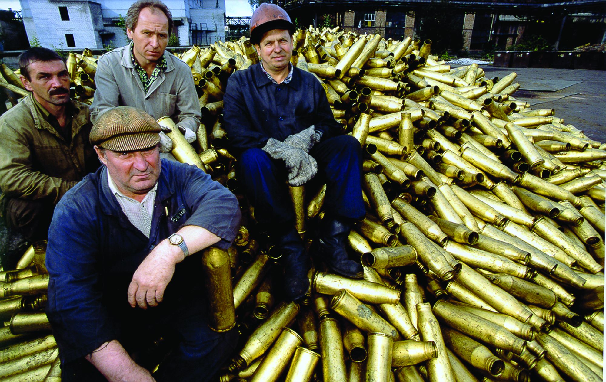 Quatre ouvriers assis sur un tas de douilles d'obus