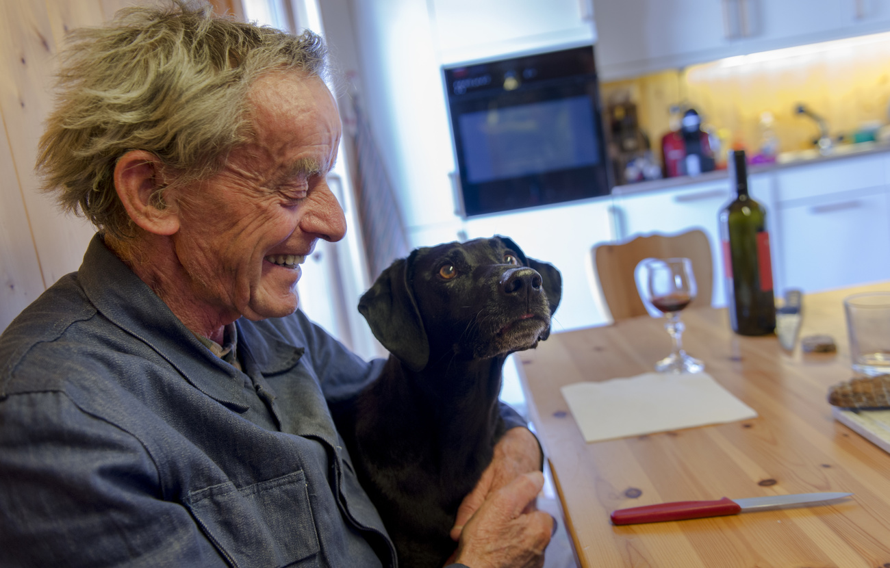 Salvatore Vitali, 76, smiles with his dog, Naco on his lap as they sit at the kitchen table in his home.