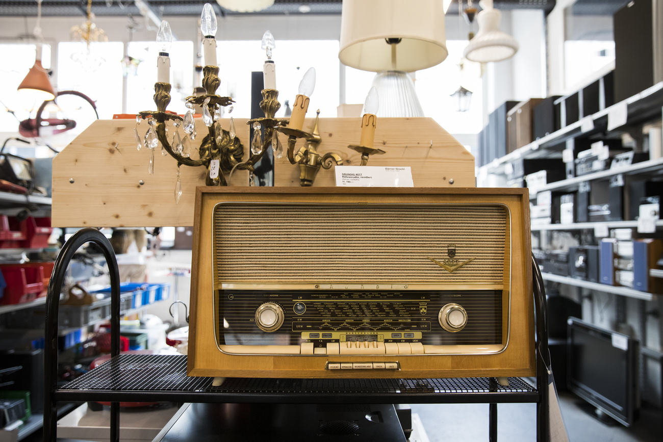 An old-fashioned brown radio in a secondhand shop. Behind it can be seen various lamps.