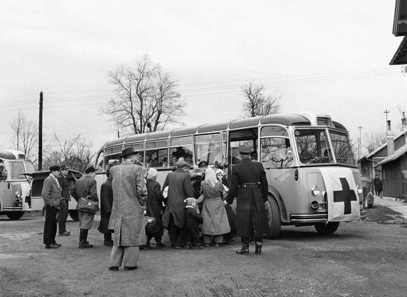 Refugees from the Hungarian revolution board a Swiss Post bus at a refugee camp in Austria in December 1956. Swiss Post sent 25 Postbuses to Austria to ensure the transport of the refugees.