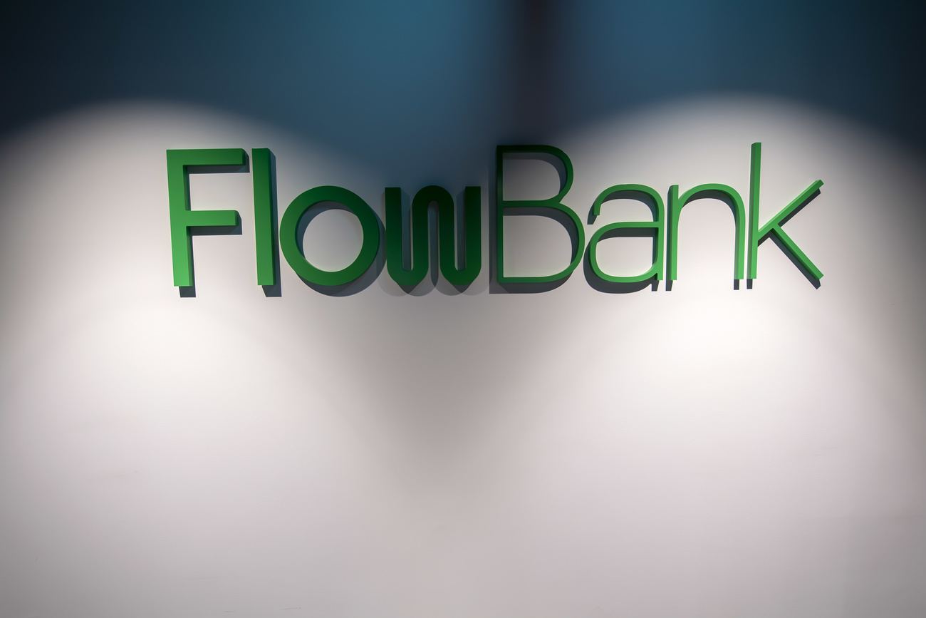 The FlowBank logo is shown on an office wall. Due to the lighting, it is partially shadowed.