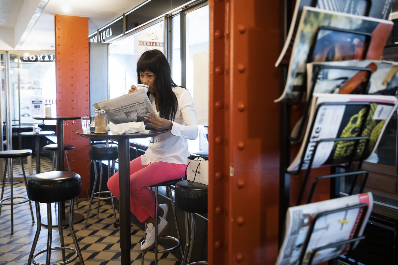 Eine Frau liest in einem Café eine Zeitung.