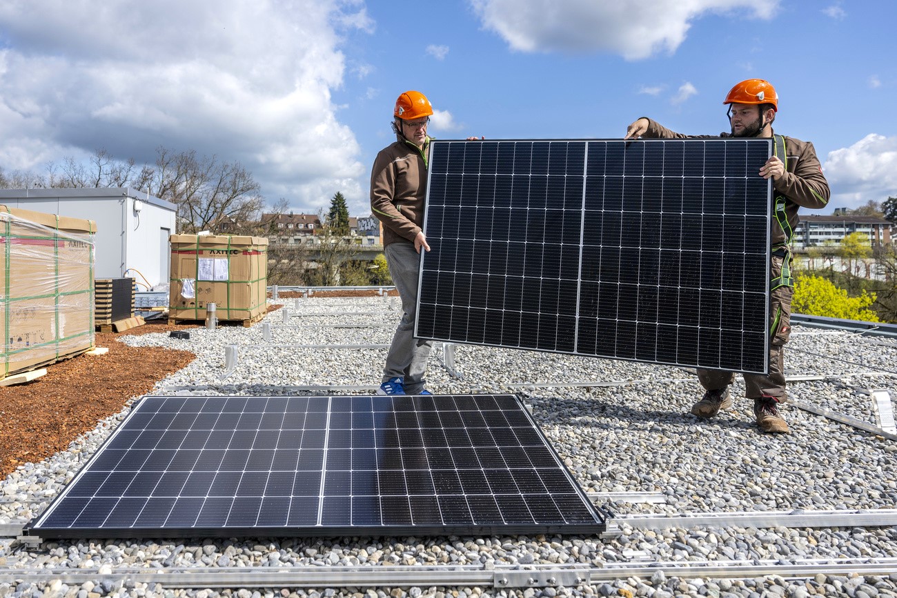 due persone stanno installando dei pannelli solari su un tetto piatto