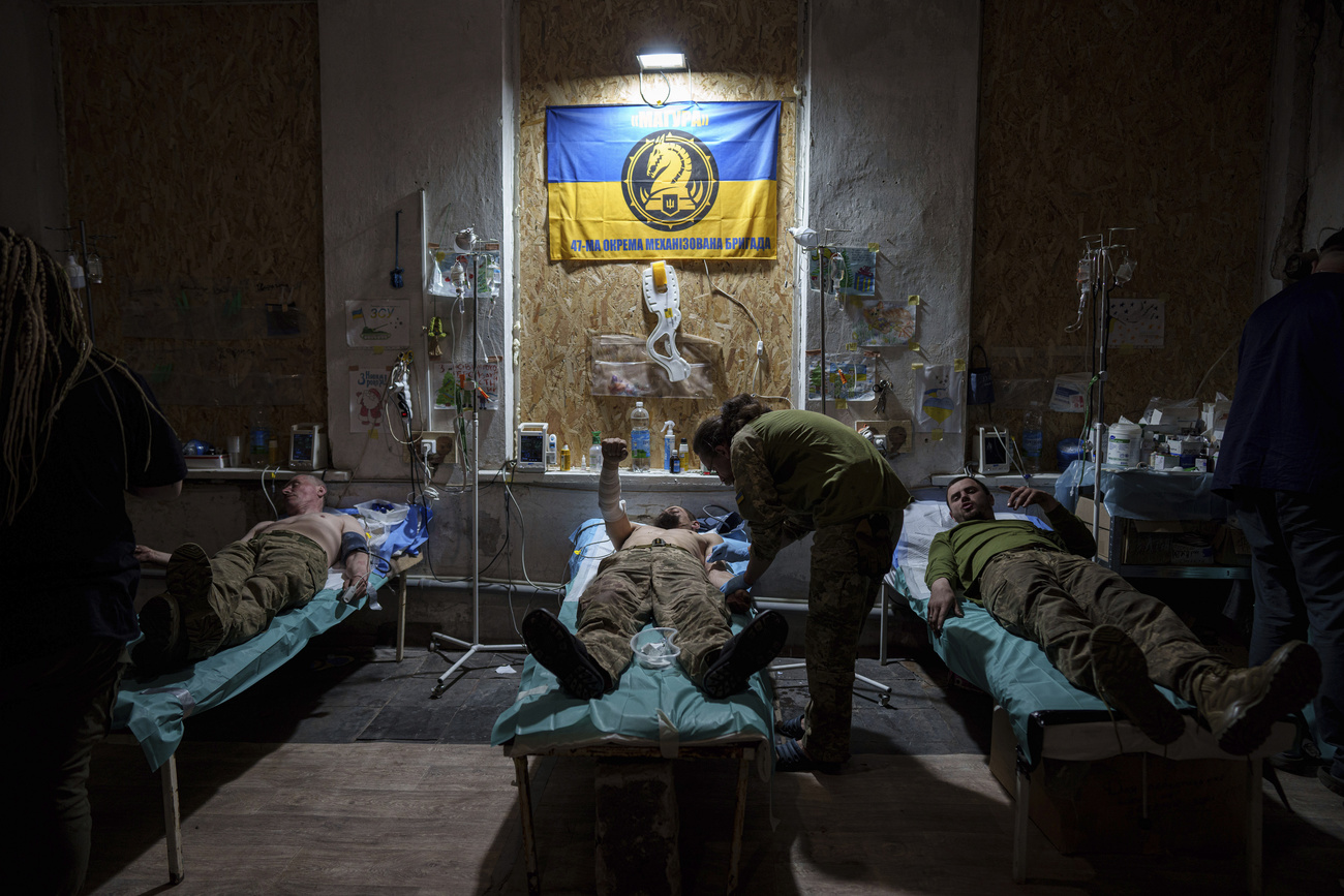 Três soldados deitados em macas e um enfermeiro