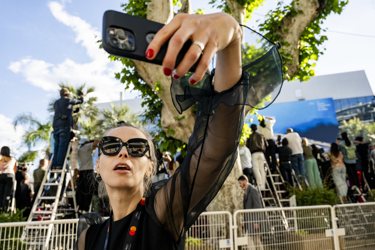 On the surface, cameras everywhere. Behind the woman taking a selfie, an army of photographers try to catch the red carpet at the festival palace. And beneath it all, the Marché du Film, where the deals are done.