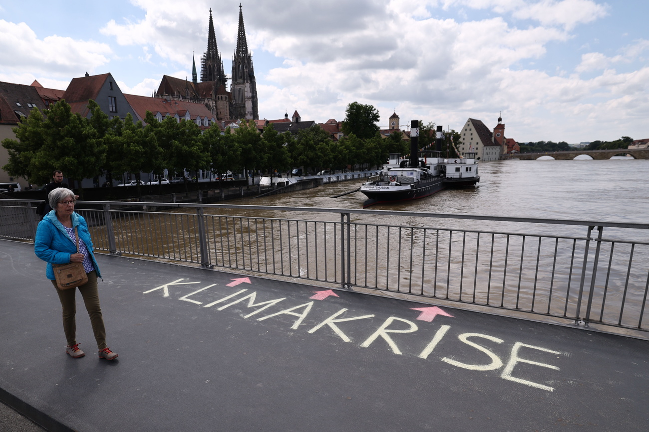 scritta KLIMAKRISE (crisi climatica) su marciapiede di ponte sopra fiume in piena