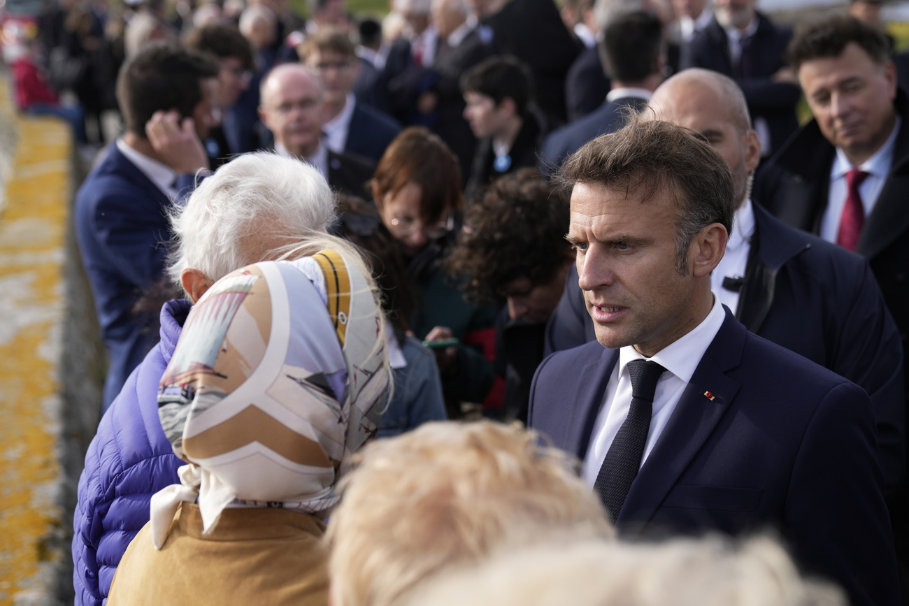 Emmanuel Macron spricht mit einer Frau mit Kopftuch.