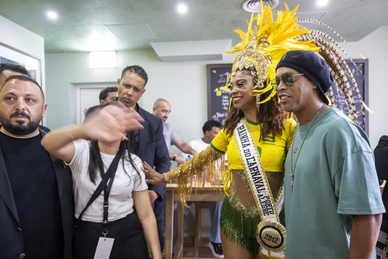 Ronaldinho arrives and poses for a few photos with a woman dressed in an elaborate Brazilian carnival costume before the inauguration of his first restaurant named after him