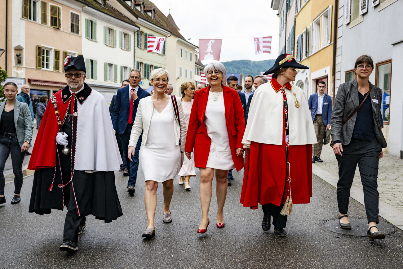 The President of the Jura Government Rosalie Beuret Siess, left, Federal Councillor Elisabeth Baume-Schneider, centre, and the President of the Jura Parliament Pauline Godat, right, march in a parade down the street