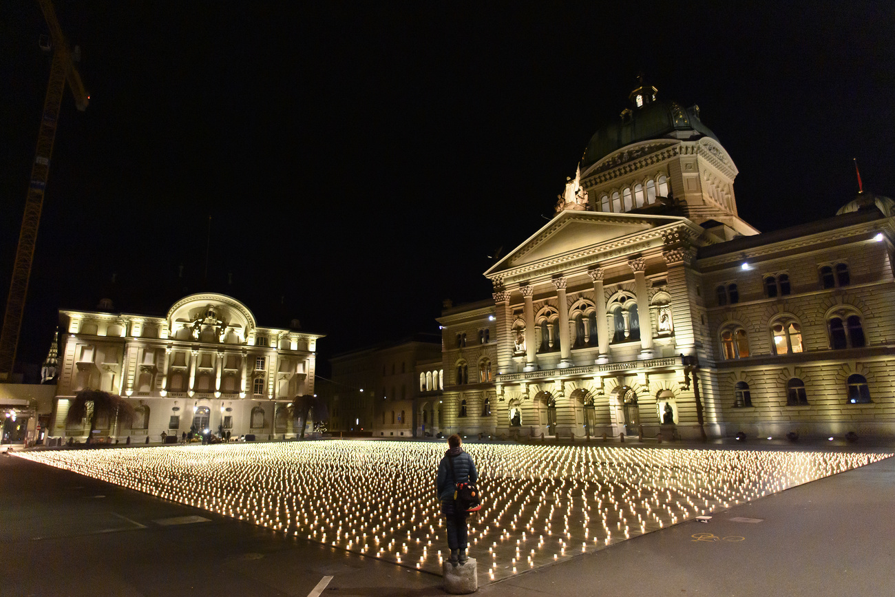 Почти 12 000 свечей в память о людях, умерших от коронавируса в Швейцарии, вторник, 7 декабря 2021 года, на площади Бундесплац перед Федеральным дворцом в Берне, Швейцария, зажгли активисты.
