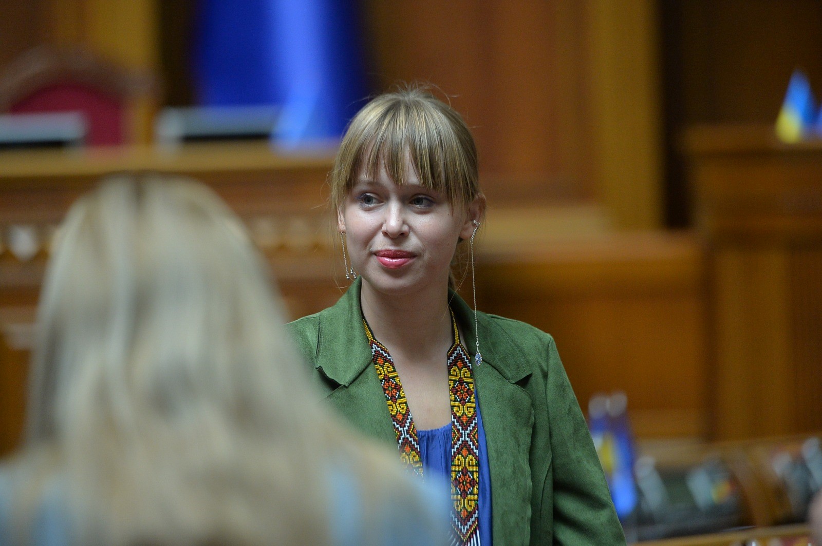 Lisa Yasko in grünem Blazer in einem Parlamentsgebäude.
