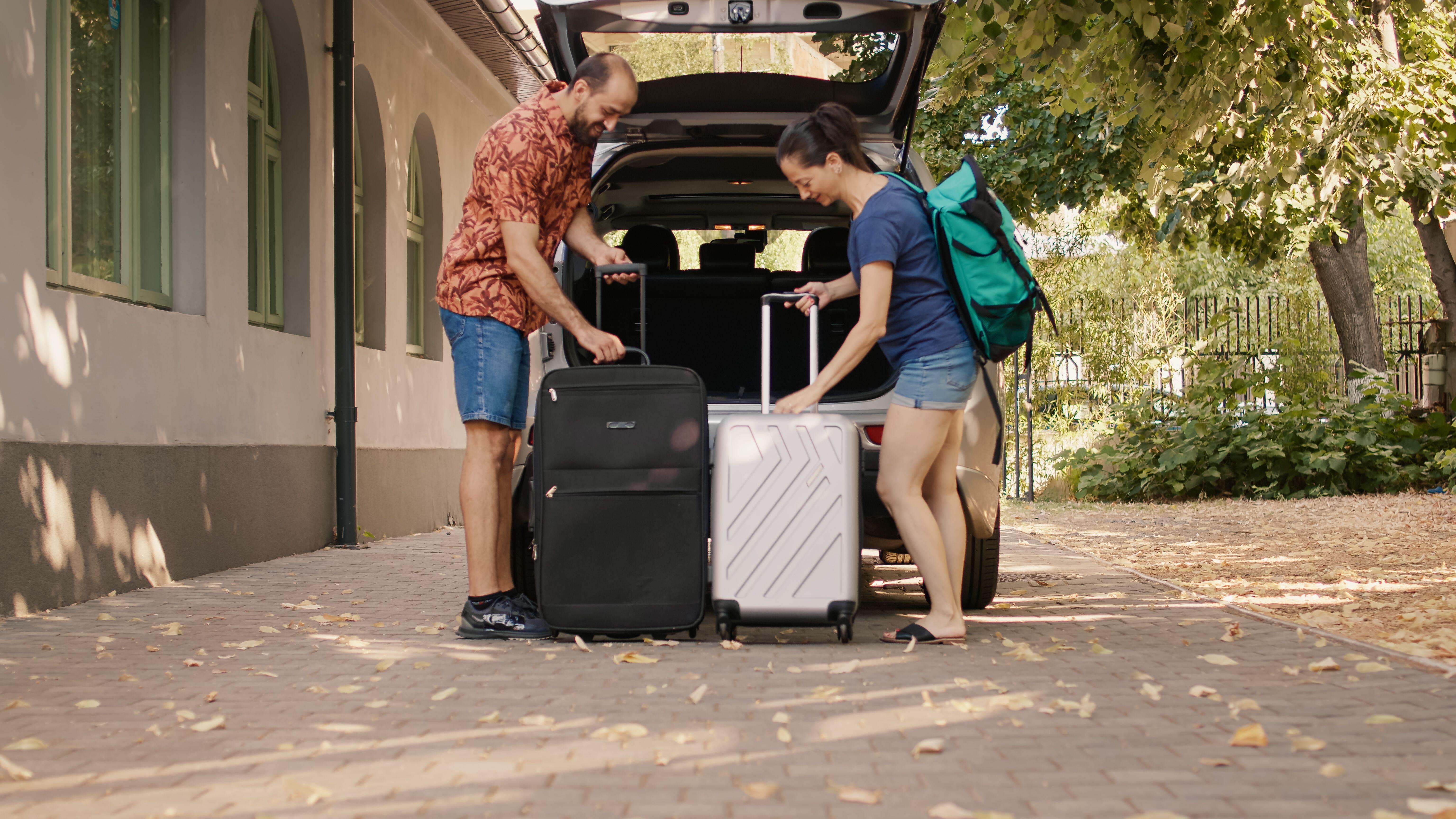 Ein Mann und eine Frau laden Koffer aus einem Auto.