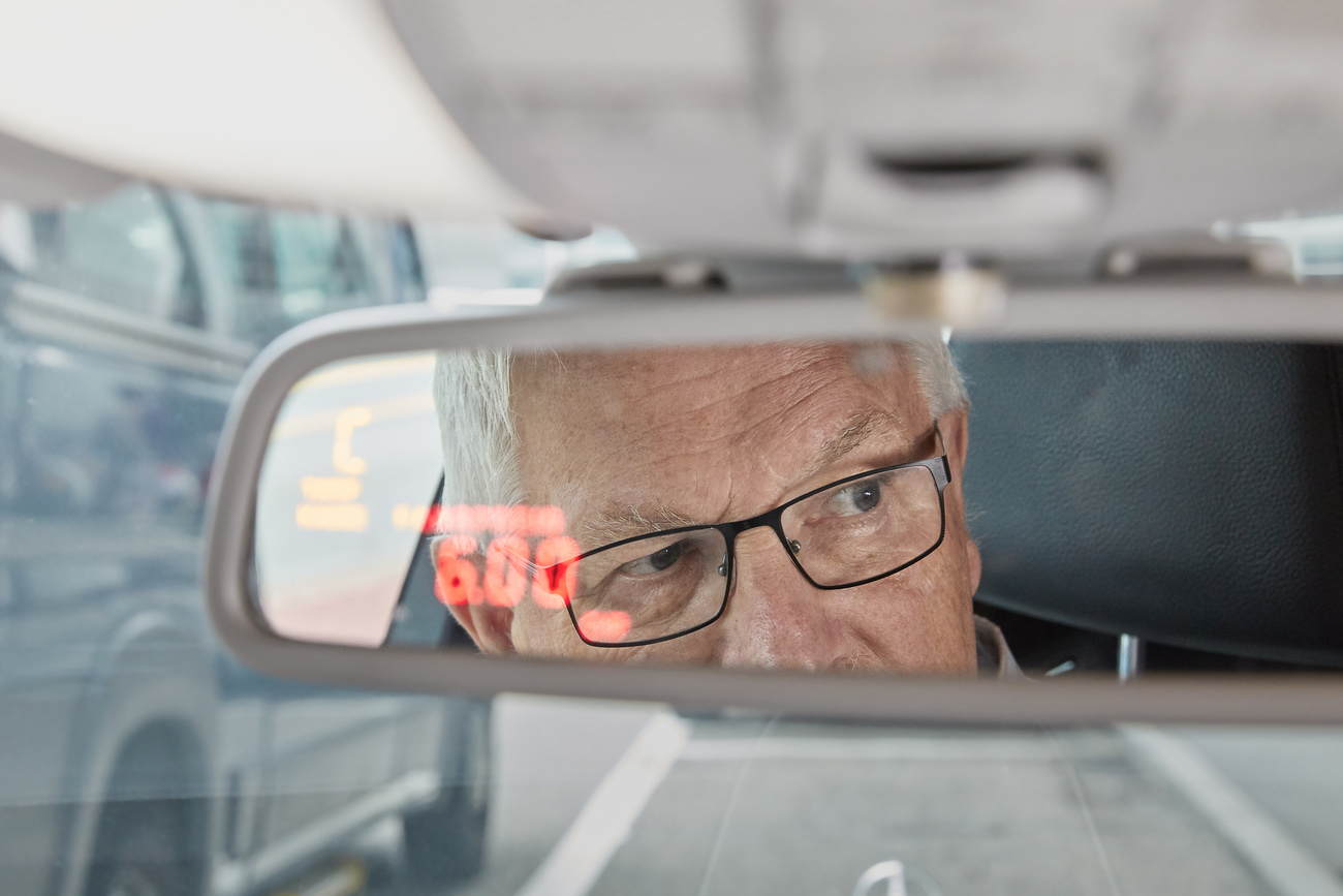 Rosto de homem idoso visto no retrovisor de um carro