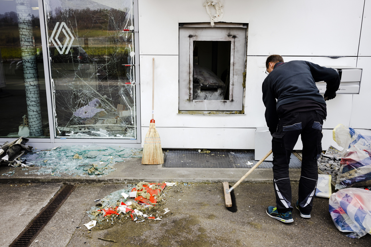 A man cleans up the remains of a blown up ATM at the Blitz Garage Volketswil, Wednesday, Dec. 22, 2021 in Volketswil.
