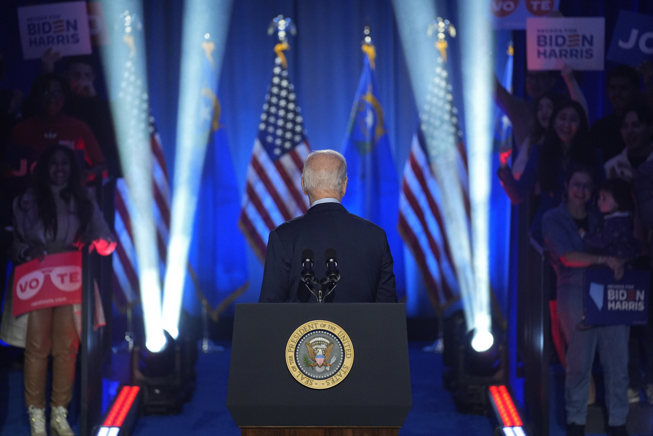 Photo of US president Joe Biden walking away from stage with US flags