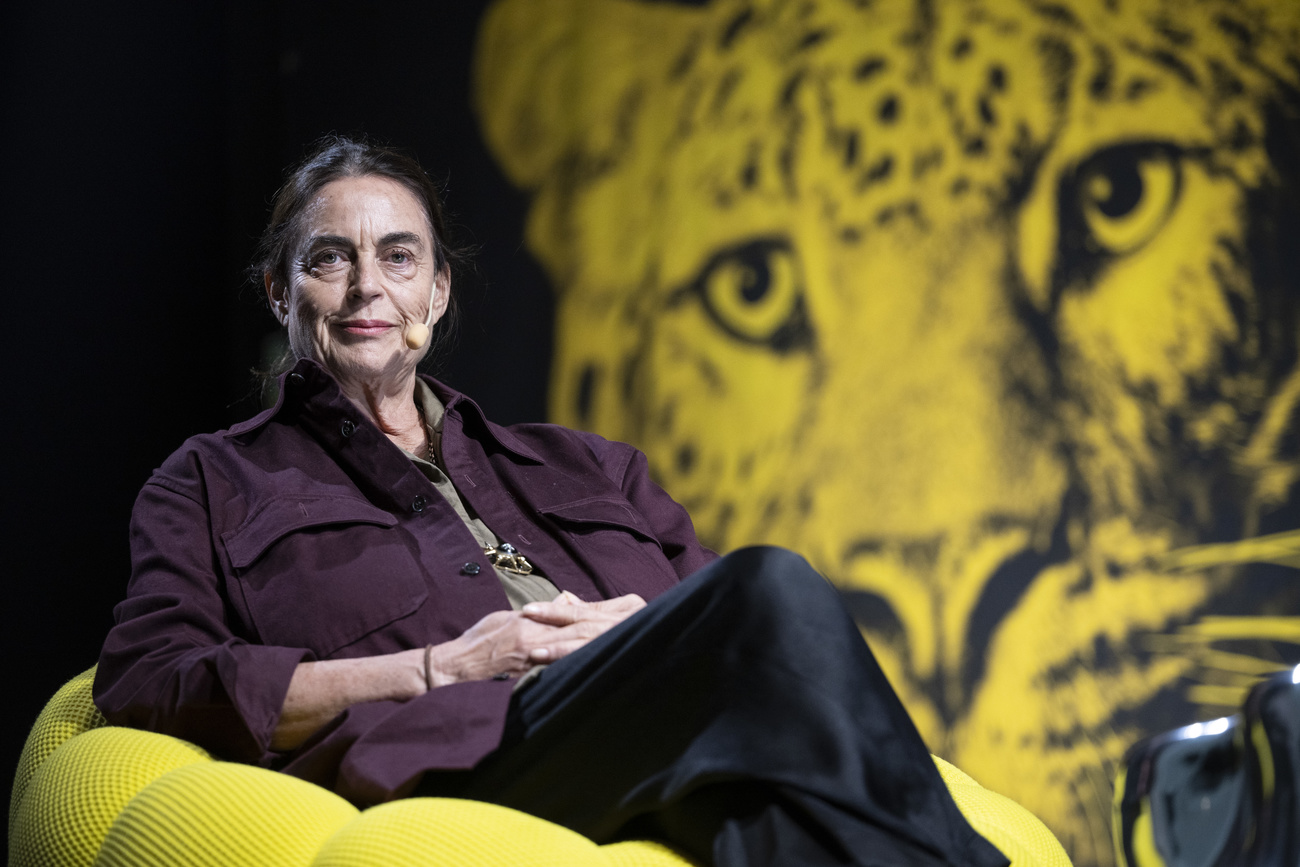 Maja Hoffmann, auf einem gelben Sessel vor einem Bild mit einem gelb gefärbten Leoparden vor schwarzem Hintergrund