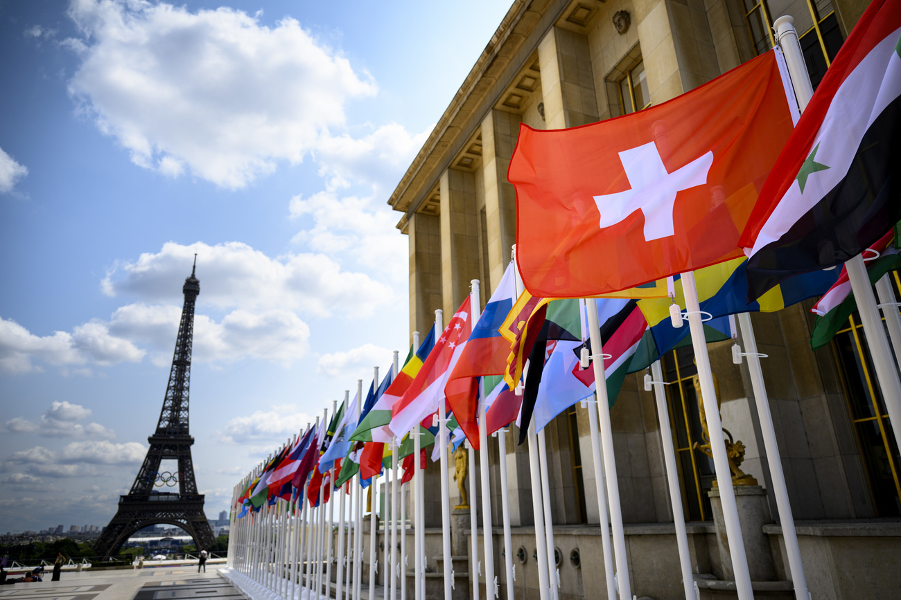 Der Eiffelturm mit den olympischen Ringen ist hinter der Flagge der Schweiz und vieler anderer Länder zu sehen