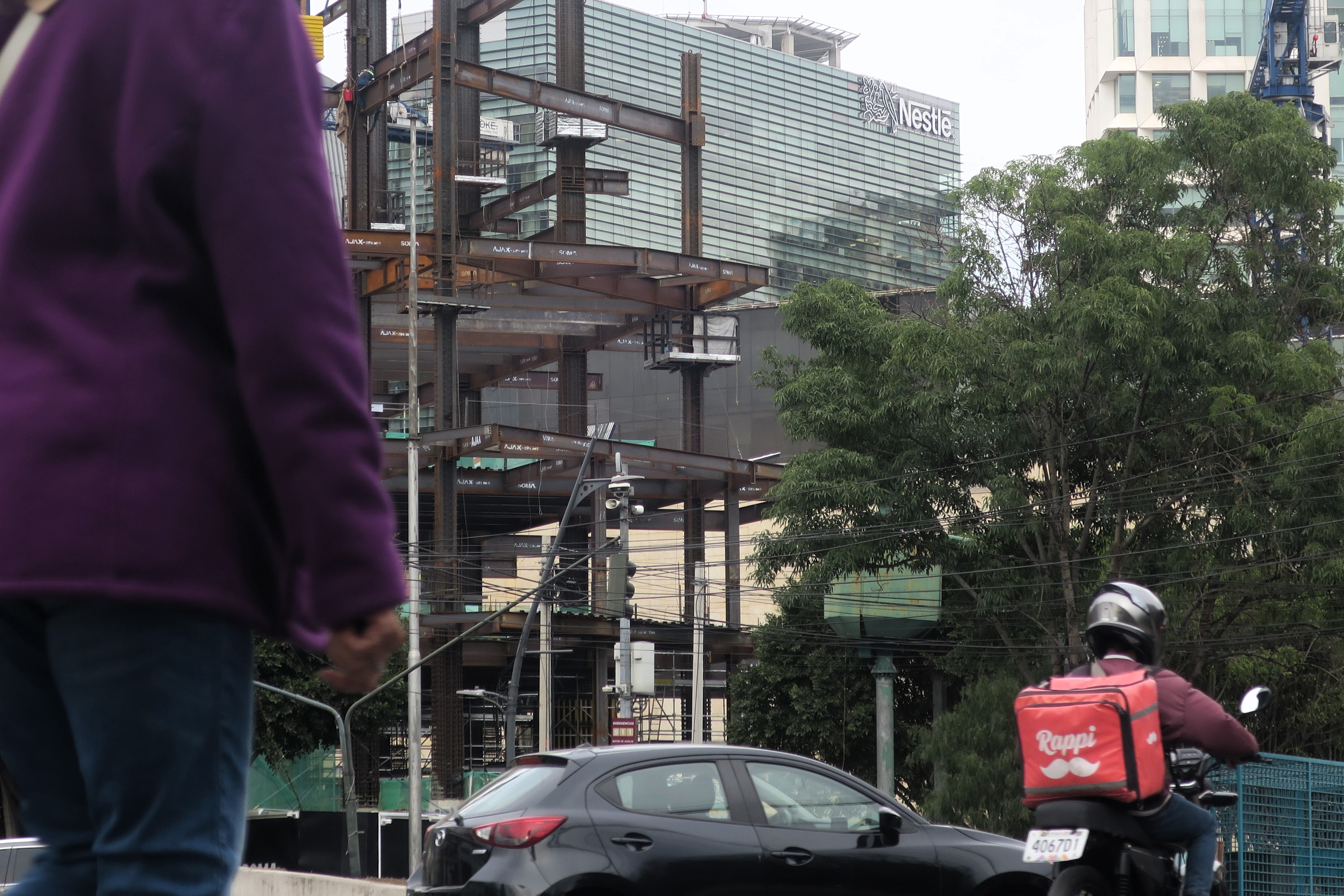 Fotografia de uma rua com carro e motoqueiro