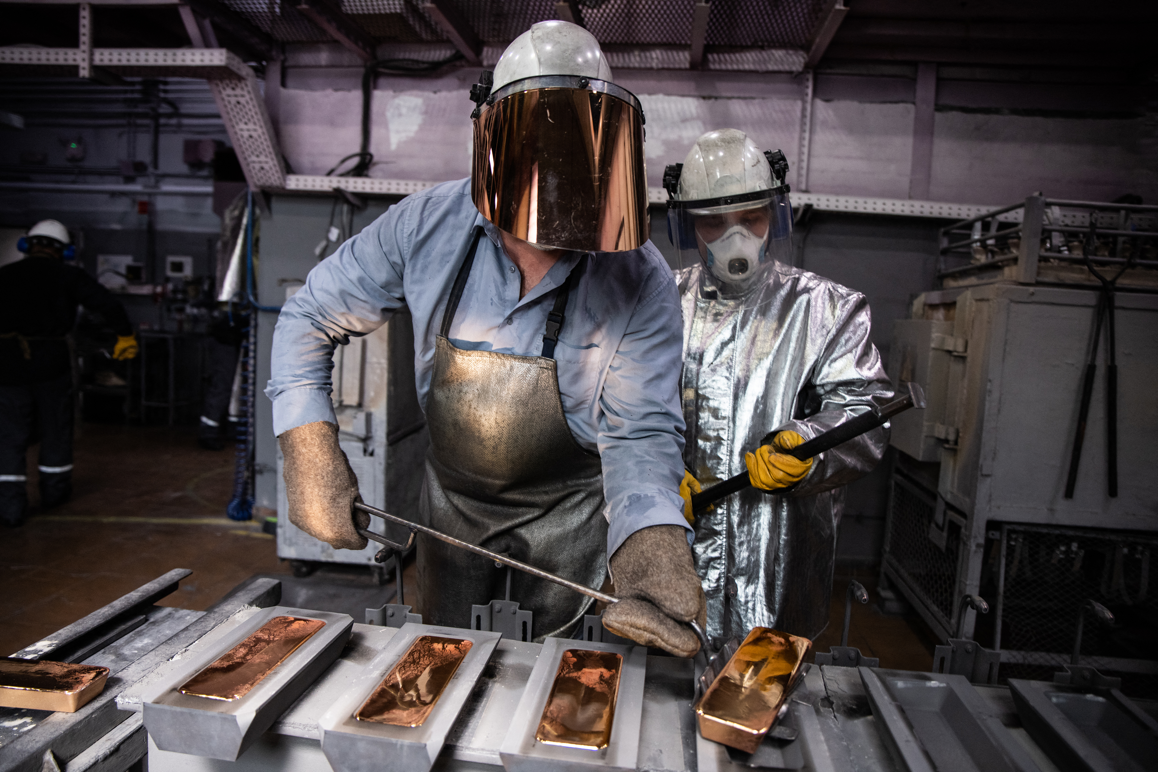 Workers at a Russian precious metals company place gold bars in a mould.