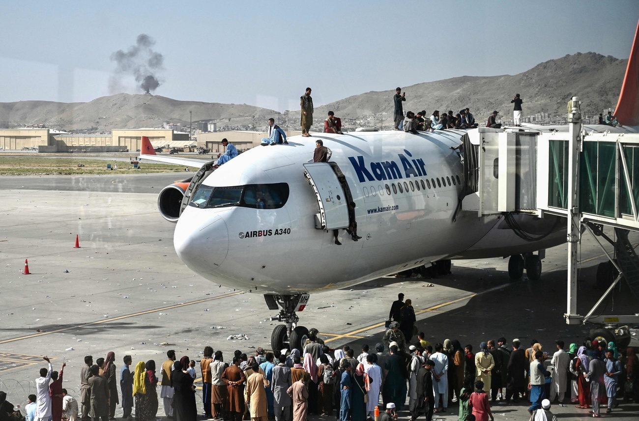 Afghan people trying to flee the capital Kabul climb on a plane at Kabul airport on August 16, 2021.