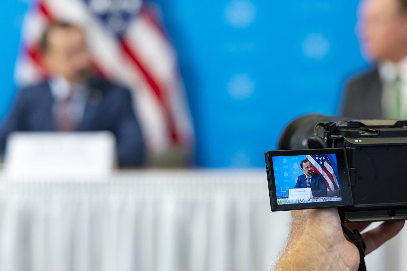 Bild von der Pressekonferenz, im Vordergrund eine Kamera, im Hintergrund verschwommen: Perriello.