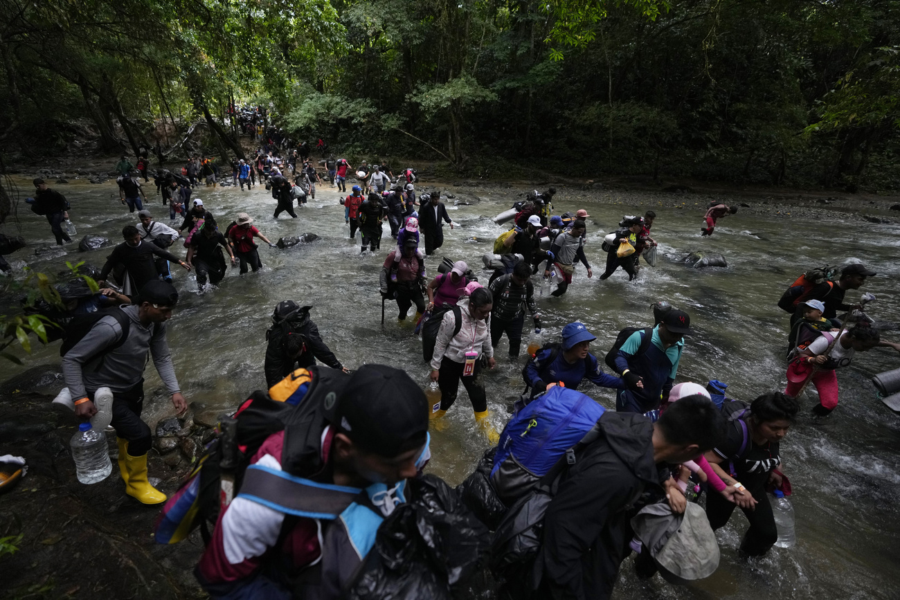 Migrantes, en su mayoría personas venezolanas, cruzan un río durante su travesía por el Tapón del Darién desde Colombia hacia Panamá, con la esperanza de llegar a los EE.UU.