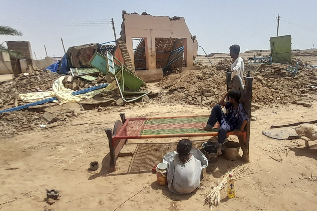 Varias personas sentadas frente a su casa dañada por las inundaciones en Meroe, al norte de Jartum, el martes. Copyright 2024 The Associated Press.