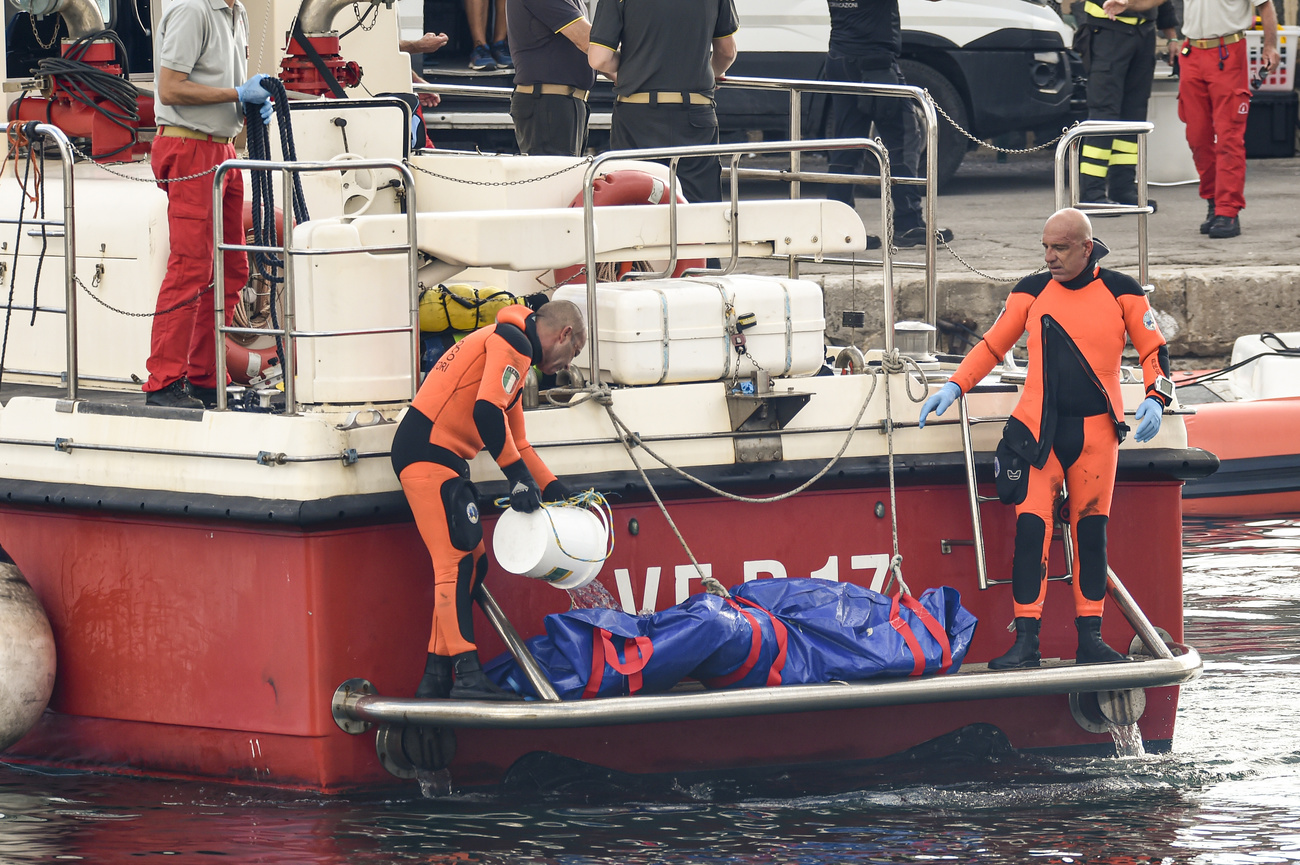 sommozzatori portano a bordo della barca una sacca contenente il corpo di una delle vittime