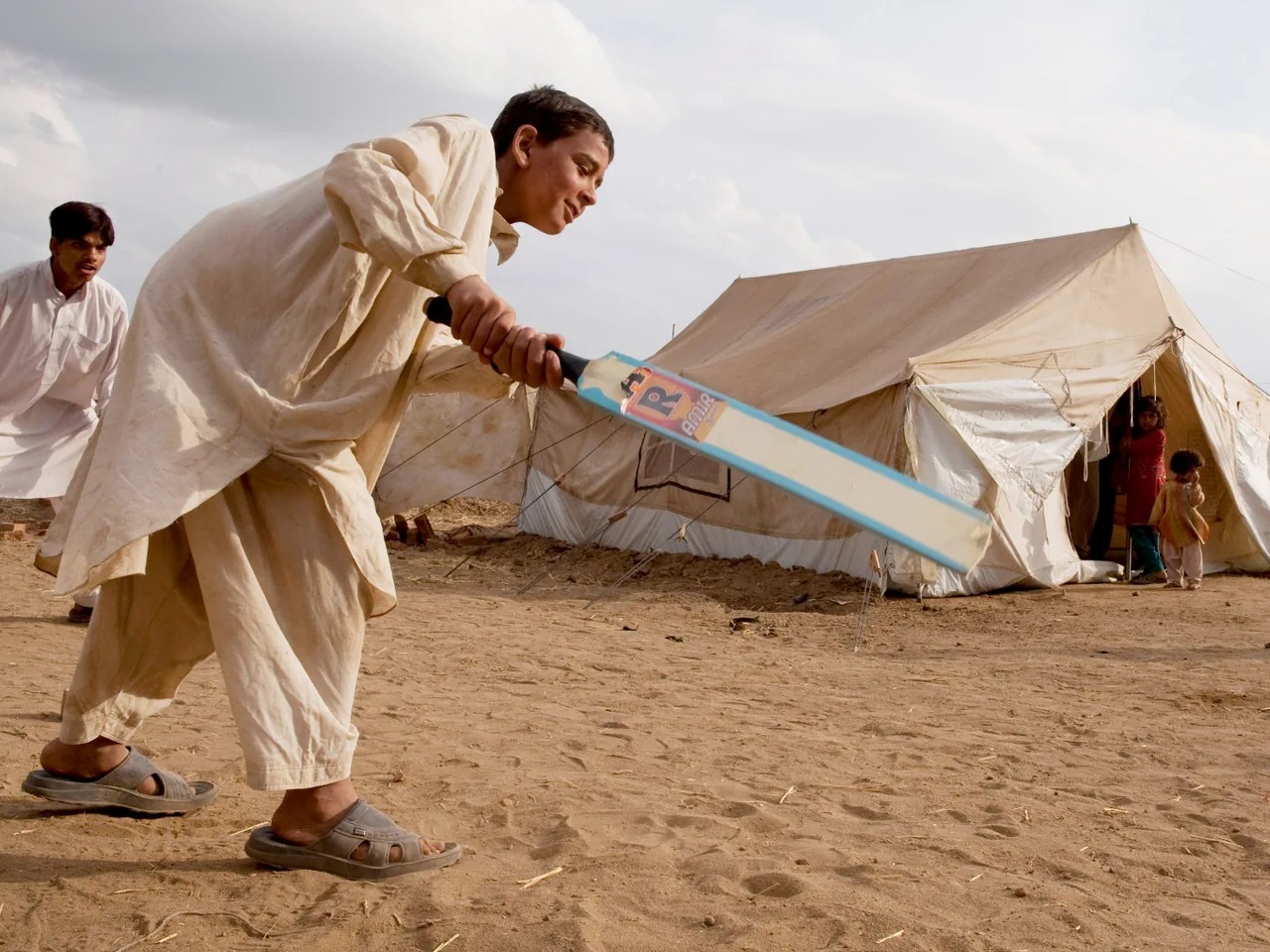 Zwei Buben spielen Cricket in einem Flüchtlingslager.