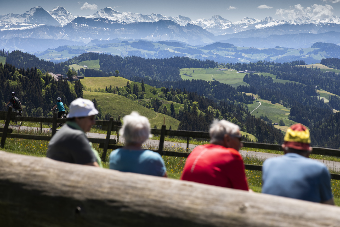 Picture of some people sitting on a bench looking at Swiss landscape