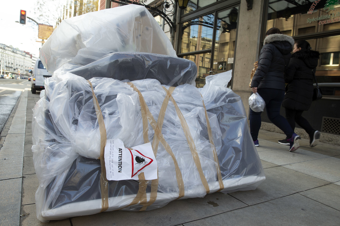 Ein Zettel mit der Aufschrift „Achtung - Dieser Gegenstand wurde entsorgt, da er mit Bettwanzen kontaminiert ist“ wird am Dienstag, den 9. Februar 2021, in Genf an einer Plastikplane angebracht, die ein Sofa, Bettgestelle und Matratzen verpackt.