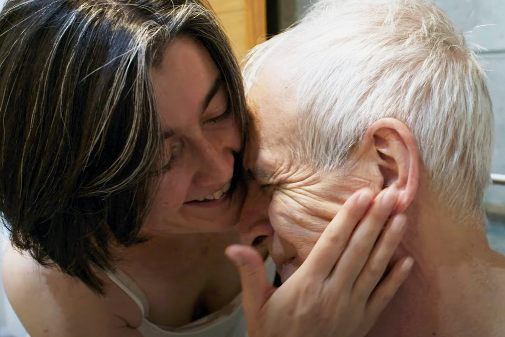 persona sorridente accarezza viso di un malato di alzheimer anziano