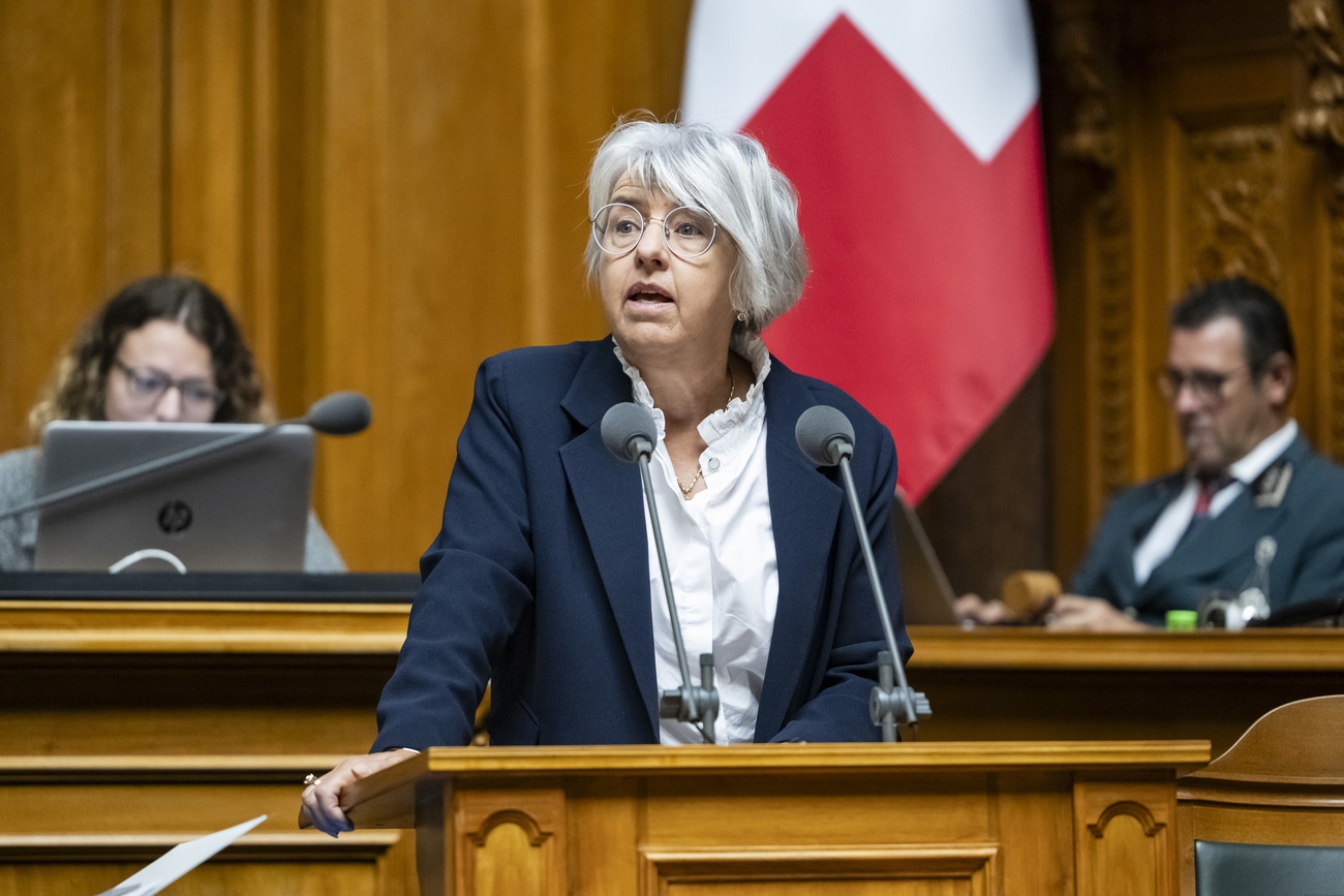 woman standing in swiss parliment in front of a swiss flag